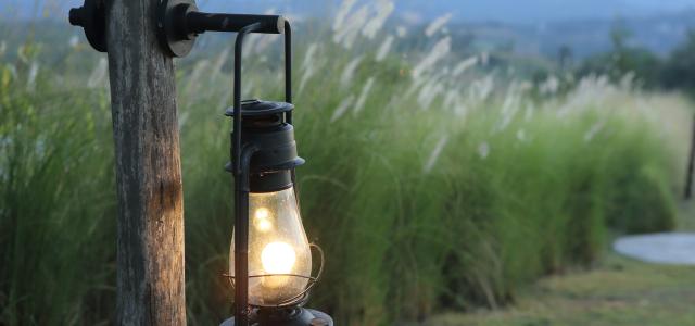 Photo of a lit lantern hanging on a post.